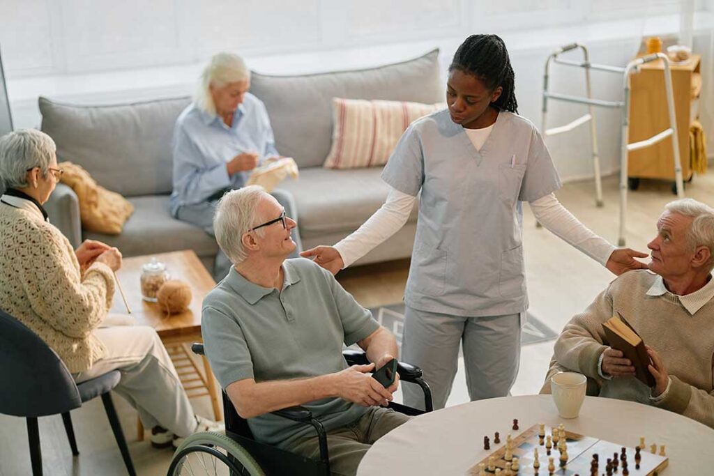 A caregiver assists an older adult with hand hygiene at a clean senior living facility table.