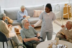A caregiver assists an older adult with hand hygiene at a clean senior living facility table.