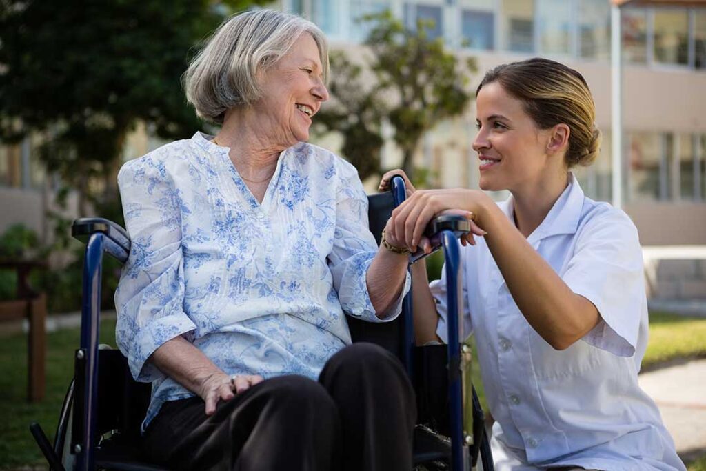 A senior adult and a middle-aged family member reviewing paperwork and discussing care options at a kitchen table.