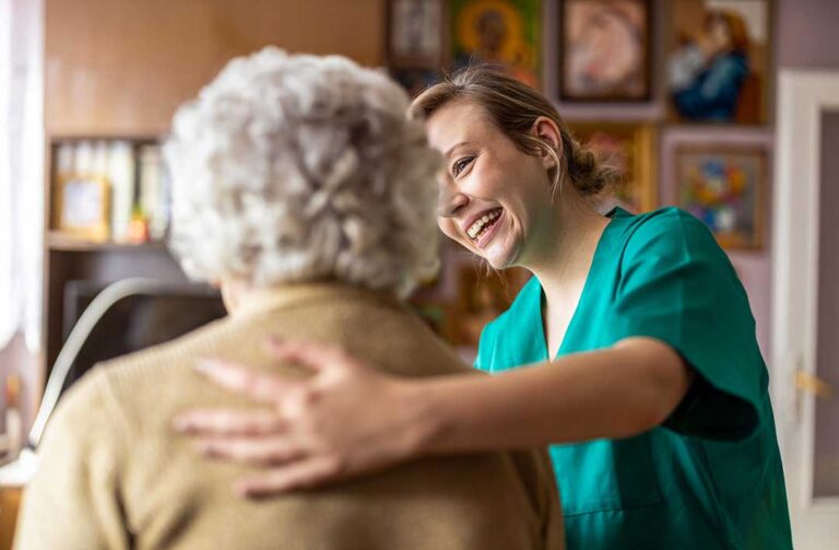 Older adult reviewing a care plan with a caregiver at a table beside a medication organizer.